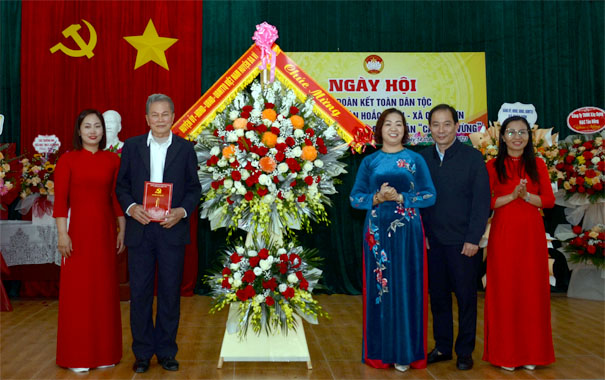 A group of people standing in front of a flower arrangementDescription automatically generated