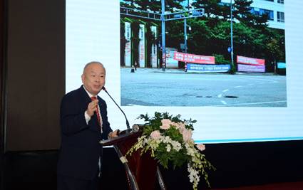 A person standing at a podium speaking into a microphoneDescription automatically generated