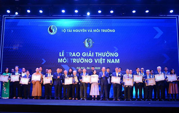 A group of people posing for a photo in front of a large screenDescription automatically generated