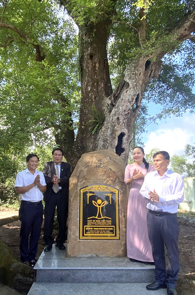 A group of people standing next to a rock with a signDescription automatically generated with medium confidence