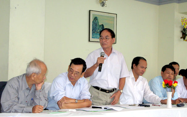 A person holding a microphone in front of a group of menDescription automatically generated with medium confidence