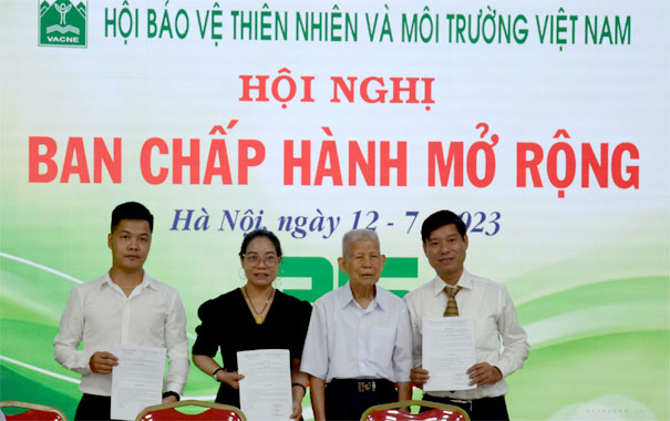 A group of people standing in front of a bannerDescription automatically generated