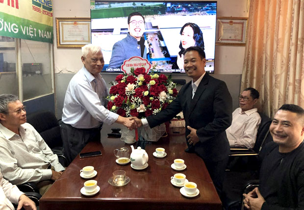A group of men shaking hands at a table with flowersDescription automatically generated