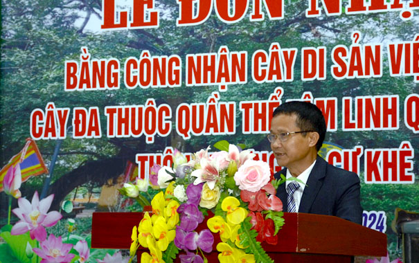 A person standing at a podium with flowersDescription automatically generated