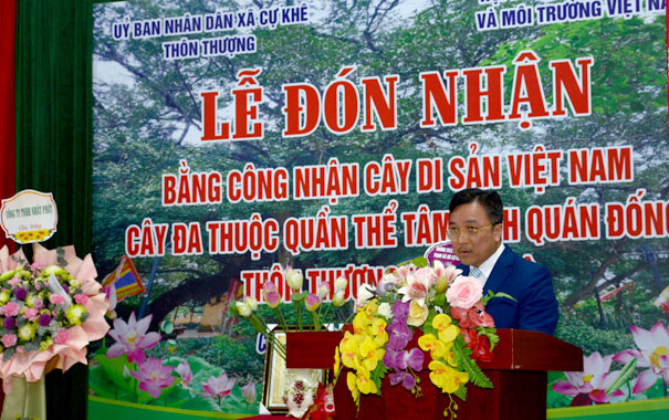 A person standing at a podium with flowersDescription automatically generated