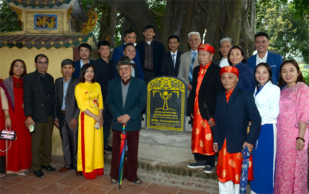 A group of people standing in front of a plaqueDescription automatically generated
