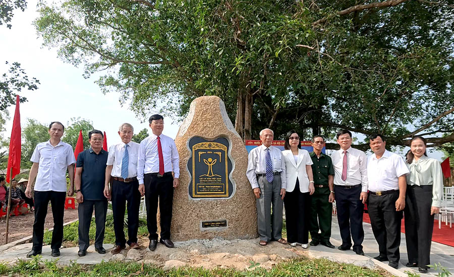 A group of people standing in front of a stone monumentDescription automatically generated