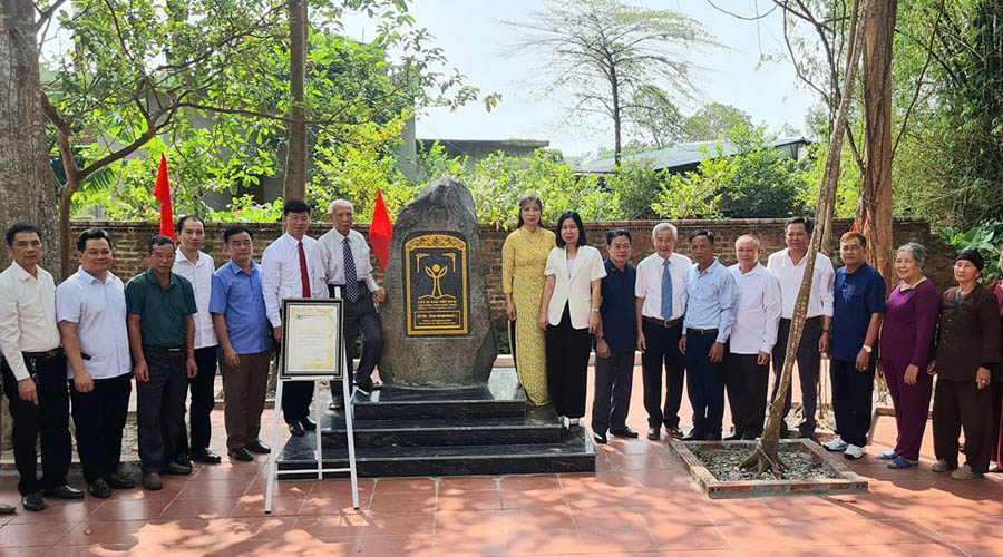 A group of people standing in front of a stone monumentDescription automatically generated