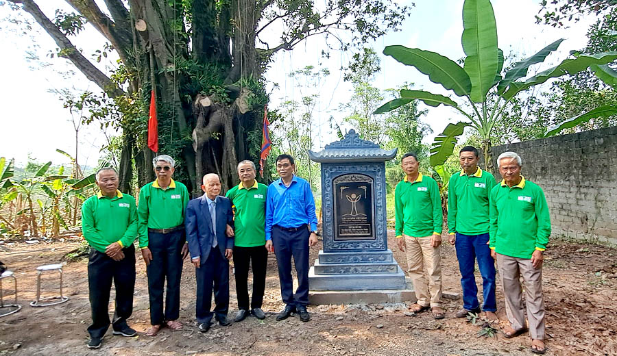 A group of people standing in front of a graveDescription automatically generated