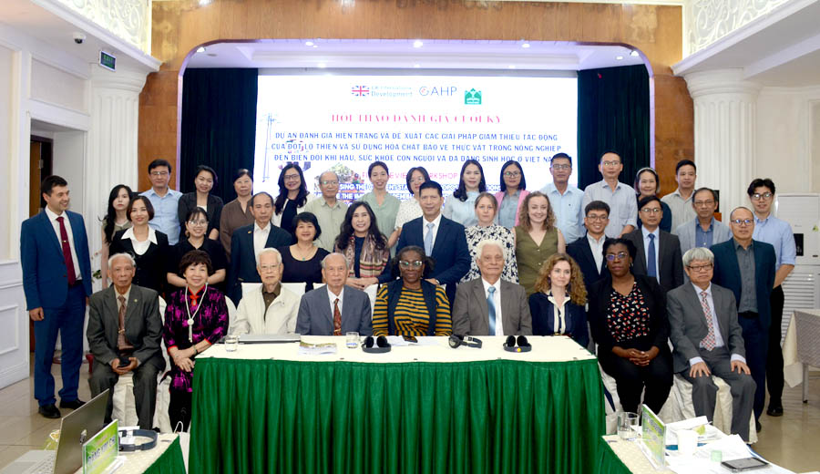 A group of people standing in front of a green tableDescription automatically generated