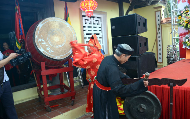 A person in a red robe playing a drumDescription automatically generated