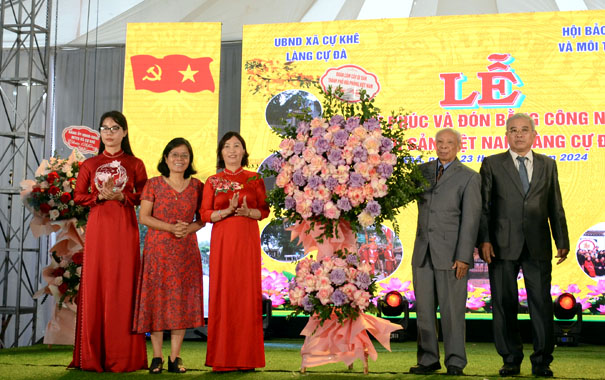 A group of people standing in front of a large flower displayDescription automatically generated