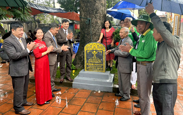 A group of people standing around a graveDescription automatically generated