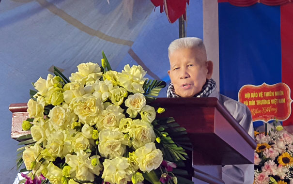 A person standing behind a podium with a bouquet of flowersDescription automatically generated
