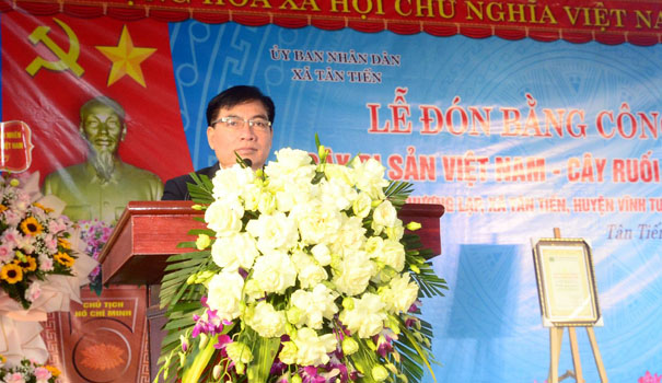A person standing behind a podium with flowersDescription automatically generated