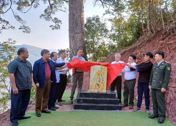 A group of people standing around a monumentDescription automatically generated