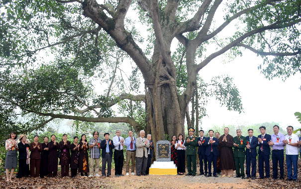 A group of people standing under a treeDescription automatically generated