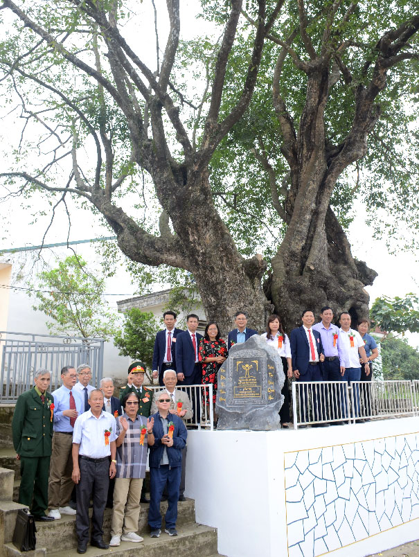 A group of people standing under a treeDescription automatically generated