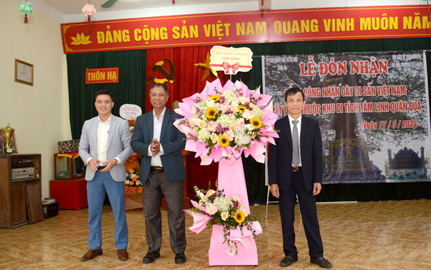 A group of men standing in front of a large pink flower displayDescription automatically generated