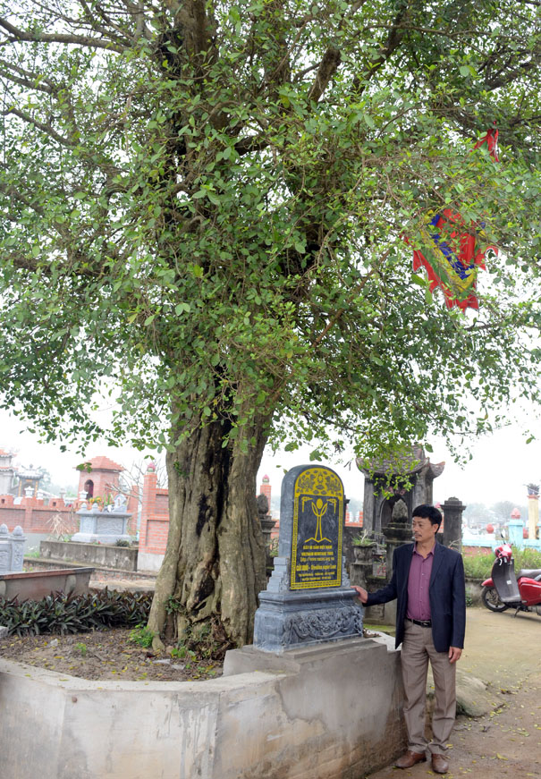 A person standing next to a grave stoneDescription automatically generated