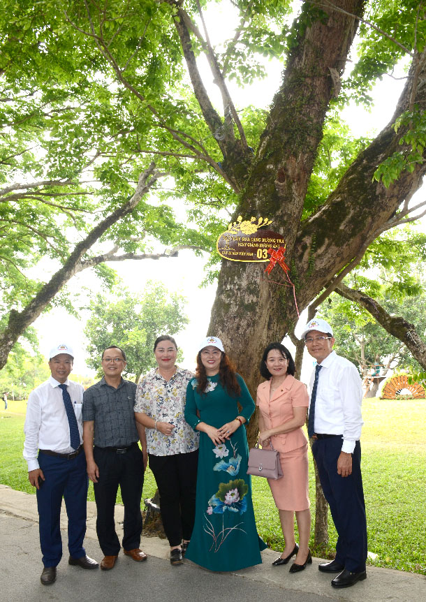 A group of people standing under a treeDescription automatically generated