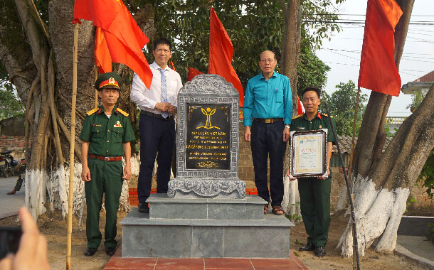 A group of men standing next to a plaqueDescription automatically generated