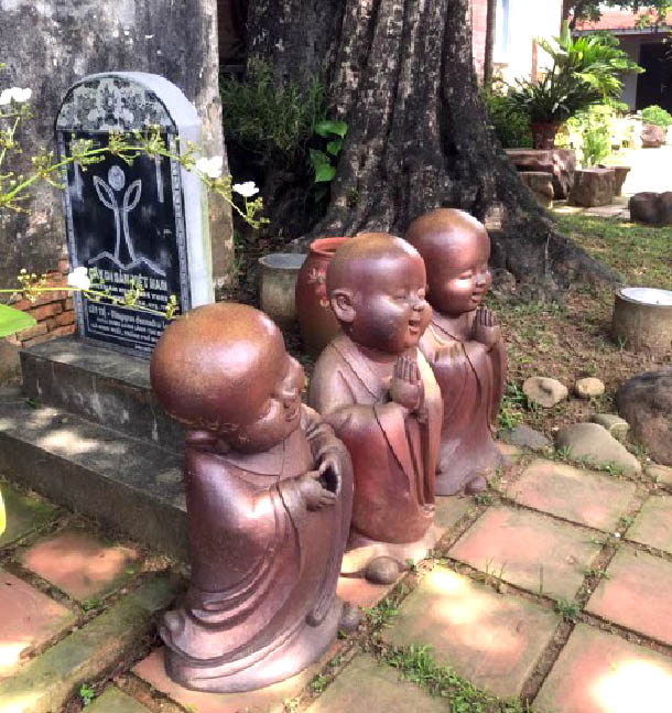 Statues of little monks in a gardenDescription automatically generated