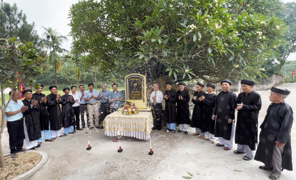 A group of people standing around a graveDescription automatically generated