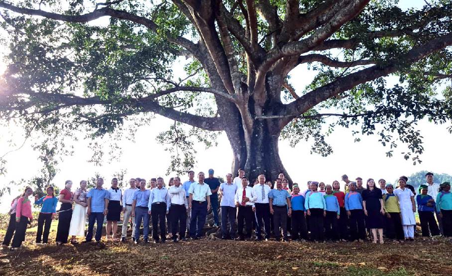 A group of people standing under a treeDescription automatically generated