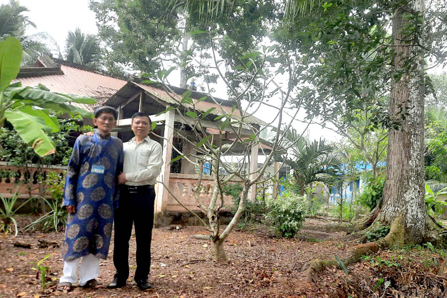 A couple of men standing in front of a houseDescription automatically generated