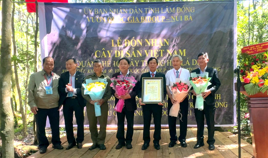 A group of people holding flowers and a plaqueAI-generated content may be incorrect.
