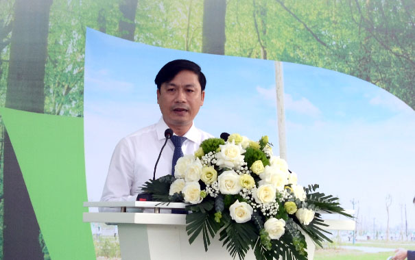 A person standing at a podium with flowersDescription automatically generated