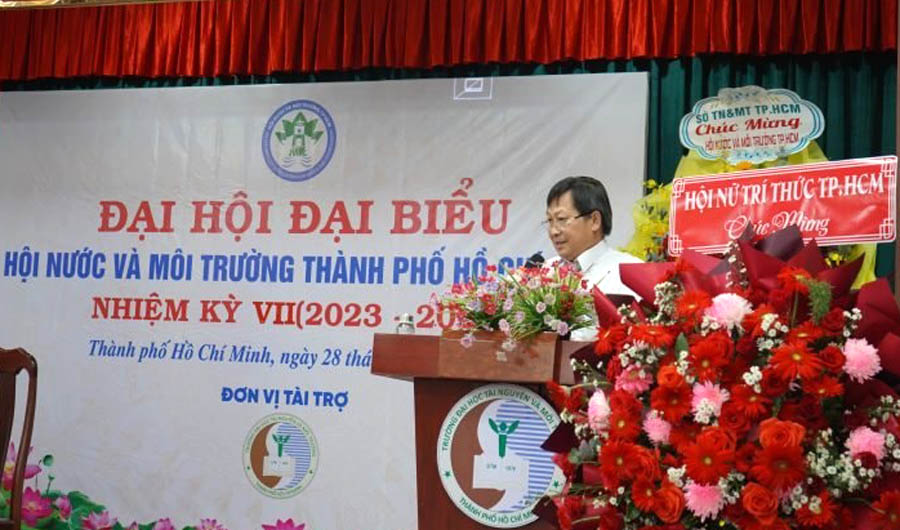 A person standing at a podium with flowersAI-generated content may be incorrect.